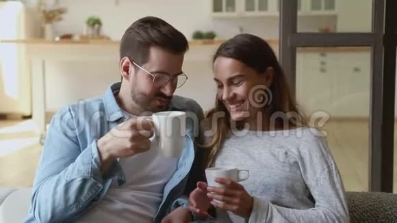 幸福相爱的夫妻在沙发上放松喝热茶视频的预览图