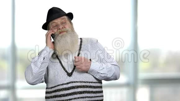 严肃的退休老人在电话里说话的肖像视频的预览图