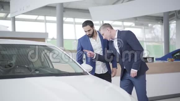 两个成年人在经销商店里讨论新的白色汽车高加索经销商和中东客户在陈列室交谈视频的预览图