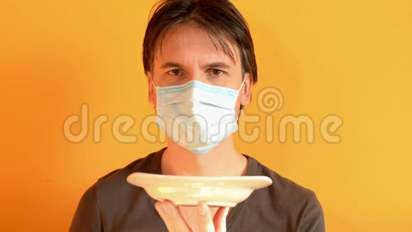 人试图用勺子从盘子里吃食物他不能用医疗面具做视频的预览图