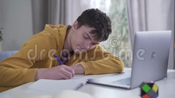 聪明的白种人十几岁的男孩睡着了在工作簿上写作努力学习的疲惫大学生的画像视频的预览图