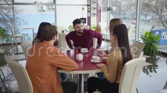 一群白人年轻人在餐馆聊天的中镜头坐在餐桌前的男女朋友视频的预览图