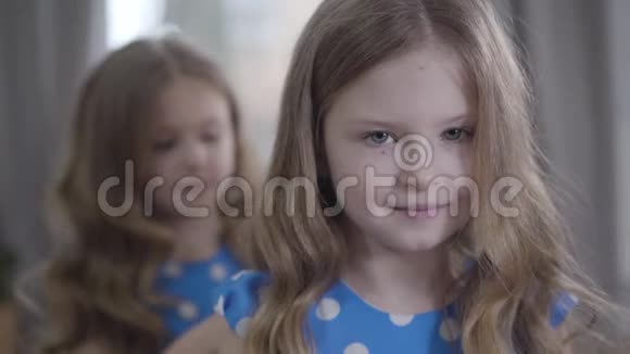 一张迷人的黑发白人小女孩的特写脸灰色的眼睛坐在室内就像她的双胞胎姐姐一样视频的预览图