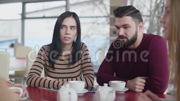 漂亮的白种人夫妇坐在咖啡馆里和模糊的朋友聊天布鲁内特的男人和女人视频的预览图