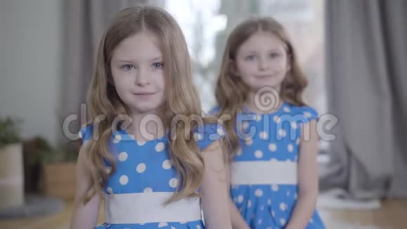 镜头接近两个漂亮的白人女孩在室内摆姿势布鲁内特的双胞胎姐妹穿着类似的衣服视频的预览图