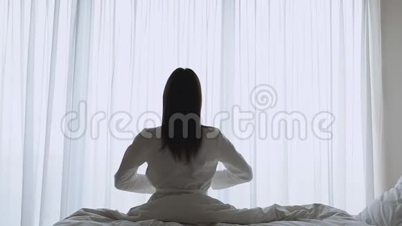 穿着丝绸睡衣的年轻黑发女人伸展手臂肌肉视频的预览图