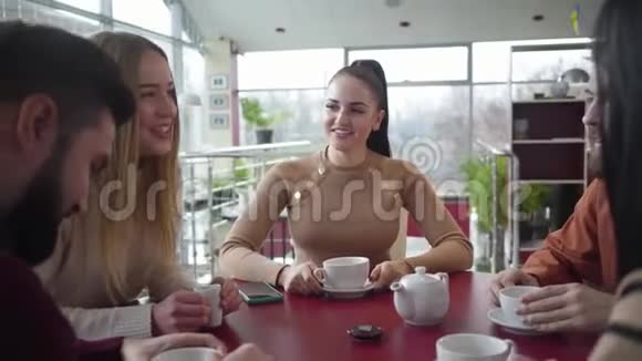 快乐的白种人黑发女人的肖像马尾辫坐在咖啡馆里和朋友一起笑积极的人视频的预览图