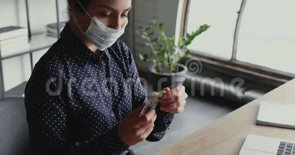 印度女商人戴着口罩用消毒凝胶清洁双手视频的预览图