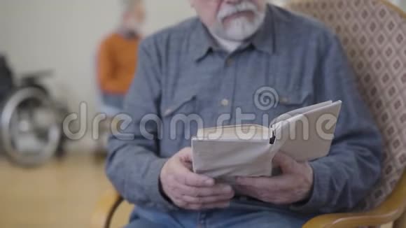 在养老院里读文学的白人老人眼镜中的模糊男性退休人员视频的预览图