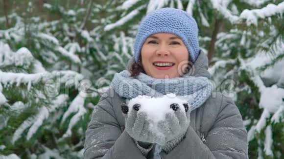 快乐的女人在松林中缓慢地吹雪视频的预览图