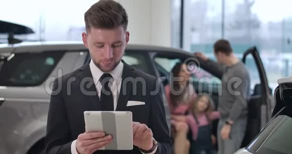 自信的年轻白种人男子使用平板电脑作为家庭交谈的背景成功的汽车经销商视频的预览图