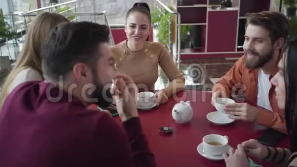 一群开朗的白人男女在咖啡馆里谈笑风生摄像机在经过的头部周围移动视频的预览图