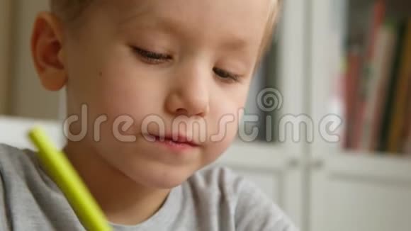 学龄前男孩幼儿拿着铅笔在桌子旁画画或做作业关门视频的预览图