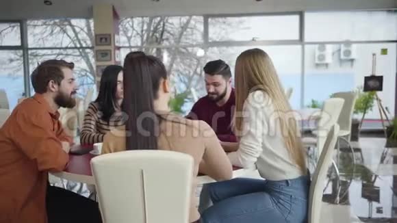 五个积极的年轻白种人坐在餐厅的桌子旁谈笑风生快乐的朋友视频的预览图