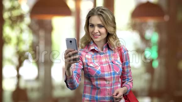 漂亮的女孩在休闲布自拍使用她的智能手机视频的预览图