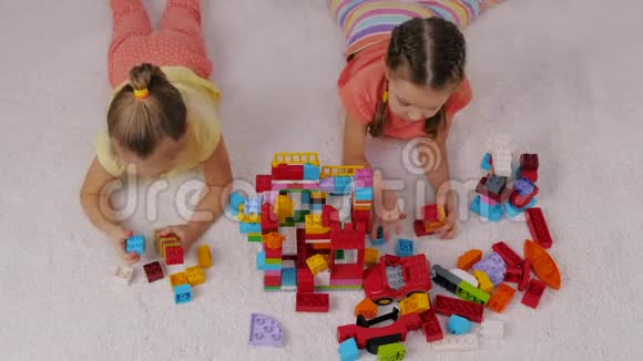 孩子们在游戏室里坐在地毯上玩彩色塑料构造器视频的预览图