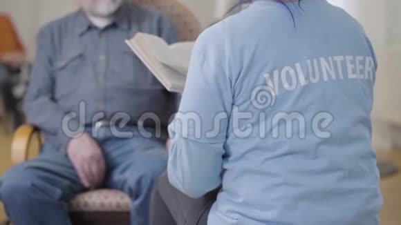 为坐在扶手椅上的模糊老人写的无法辨认的志愿者读物在养老院做义工成熟成熟视频的预览图