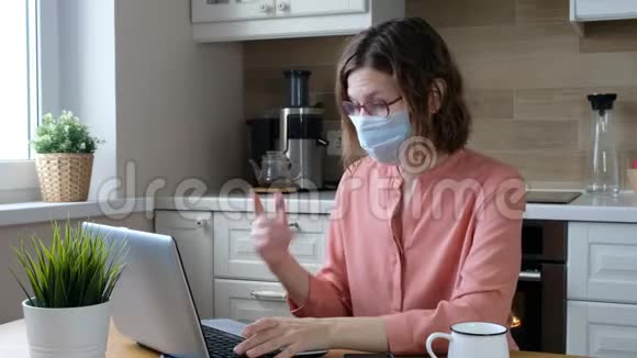 戴着医用口罩的女人在家里工作科罗纳病毒检疫隔离期视频的预览图