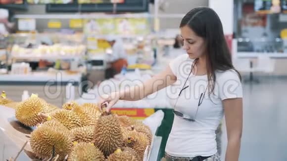 年轻的女游客在超市挑选成熟的水果闻一闻然后取一个视频的预览图