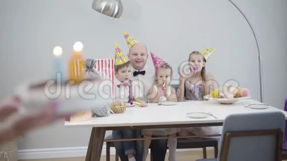 女性白种人的双手带着40号的生日蛋糕到桌子上成年男子吹灭蜡烛孩子们视频的预览图