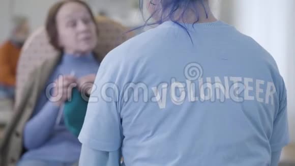 无法辨认的白种人志愿者在养老院和模糊的老妇人交谈少女志愿服务的后景视频的预览图