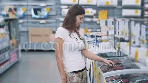 3年轻女子在家电商店里选购洗衣机视频的预览图