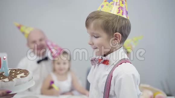 侧视特写白种人男孩戴着派对帽站在女手上给他看生日蛋糕快乐的孩子视频的预览图