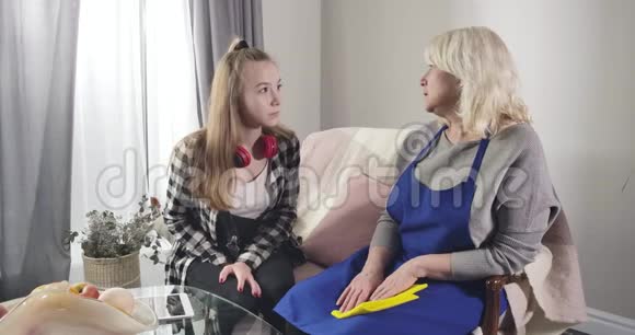 十几岁的白人女孩坐在沙发上让祖母心烦意乱让她平静下来年长的金发女人在分享视频的预览图