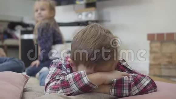 特写画像上可爱的小白种人男孩藏着脸妹妹坐在后台欢乐的孩子们视频的预览图