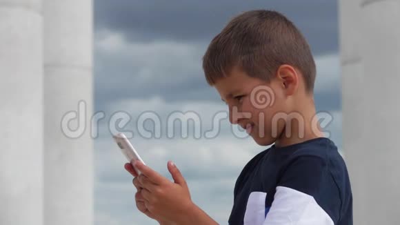 严肃的男孩正在看他手中的电话视频的预览图
