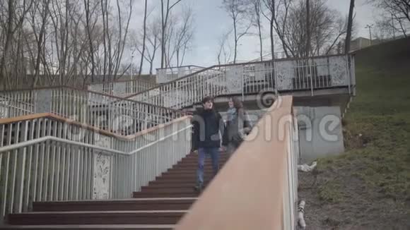 快乐的白人夫妇的学生走下楼梯在城市公园和离开小伙子和姑娘聊天视频的预览图