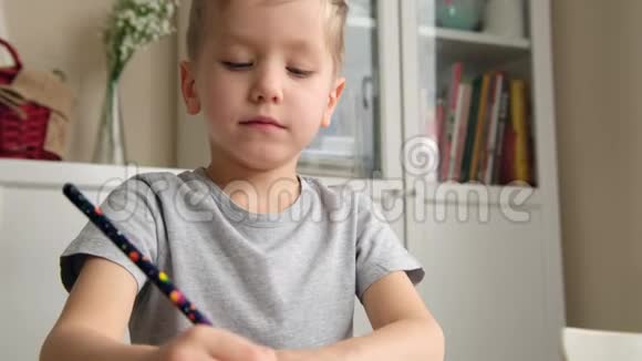 学龄前男孩幼儿拿着铅笔在桌子旁画画或做作业视频的预览图