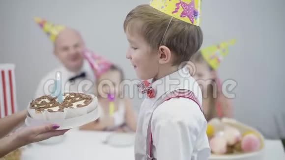 小白种人男孩在生日蛋糕上吹灭了图四上的蜡烛派对帽庆祝的年轻人视频的预览图