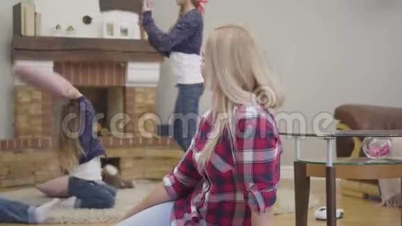 一幅美丽的白种人金发女人坐在地毯上回头看着穿着类似衣服的快乐女儿的画像视频的预览图