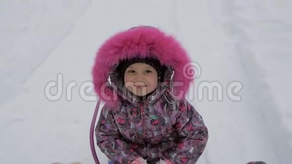 一个小女孩喜欢坐雪橇父母用雪橇载着孩子视频的预览图