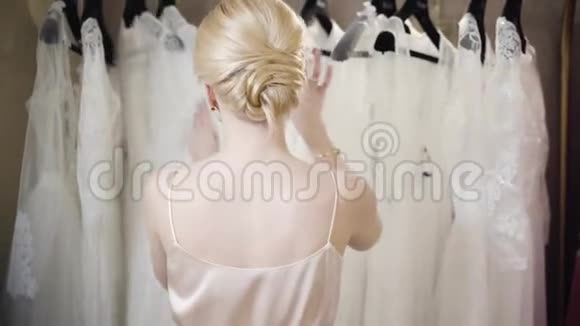 年轻的金发白种人女人选择时装在精品店时髦漂亮的女士站在架子前视频的预览图