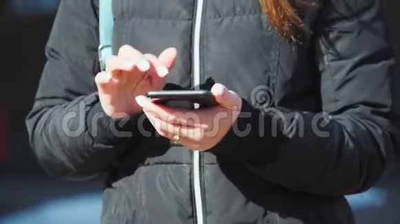 在稳定器上射击一个穿着黑色夹克的女孩拿着电话看不到脸特写视频的预览图
