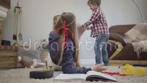 一个年轻的白种人女孩的特写镜头回头和弟弟妹妹用枕头打架小可爱视频的预览图