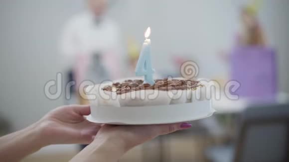 镜头跟随生日蛋糕到桌子上家人戴着派对帽妈妈带着4号和儿子的馅饼视频的预览图