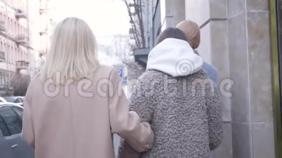 在城市里漫步的三个白人年轻女性的后景美丽的女孩在户外沿街散步聊天视频的预览图