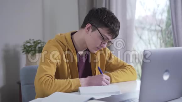 集中白人青少年戴眼镜做作业的肖像智能大学生从笔记本电脑阅读视频的预览图