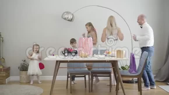 幸福的大白种人家庭的肖像互相拿着衣服绕着桌子移动快乐的人聚会视频的预览图