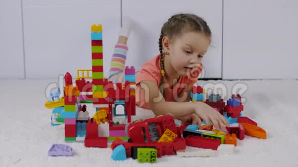 可爱的小女孩躺在地毯上玩着五颜六色的乐高积木视频的预览图