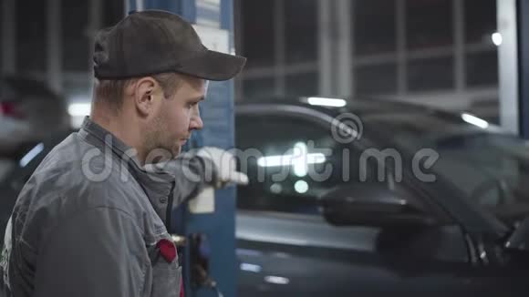 专业高加索汽车修理工用设备养车的侧视图严肃的成年男子视频的预览图