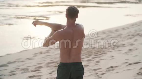 肌肉发达的人在日落时在海滩上做运动动作缓慢视频的预览图