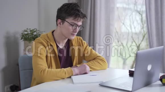 侧面看疲惫的白人聪明男孩摘下眼镜和揉鼻子出色的大学生完成任务视频的预览图
