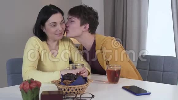 十几岁的白人黑发男孩亲吻妈妈的脸颊积极的儿子晚上和妈妈在家快乐的女人视频的预览图