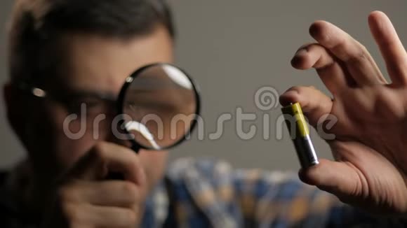 一个人通过放大镜检查AA电池视频的预览图