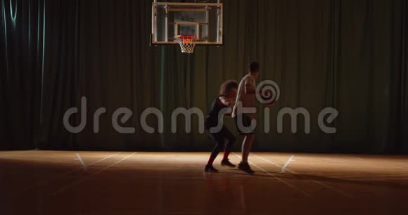 两名年轻的篮球运动员进行篮球比赛业余选手进行场地运动球拍剪影运球视频的预览图