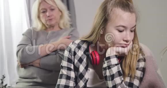 特写白种人年轻女孩的肖像无视祖母坐在后台成熟的金发女人视频的预览图